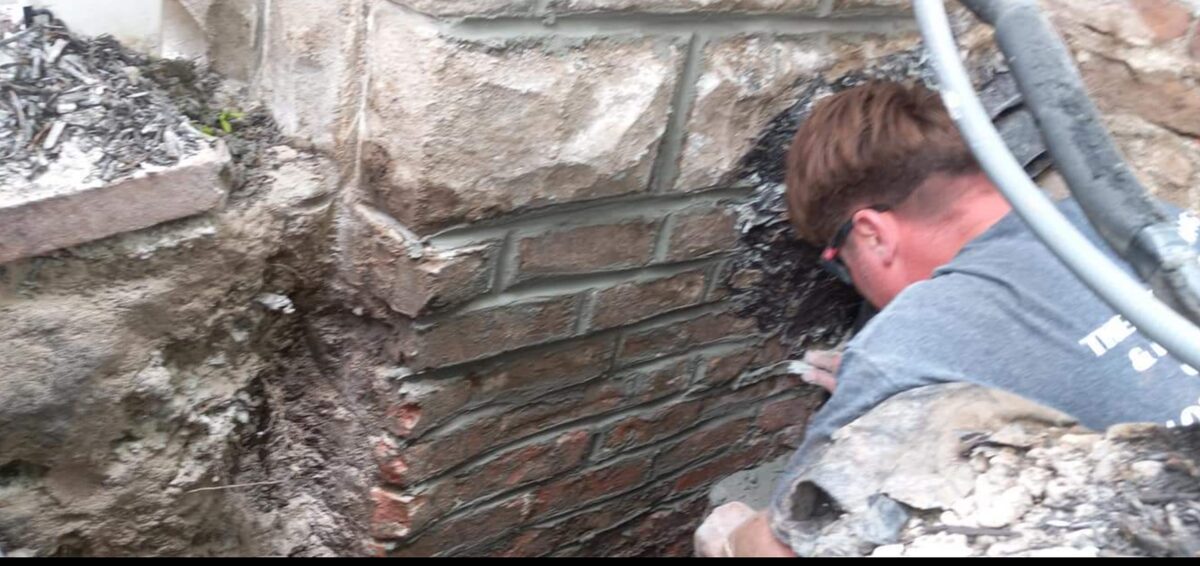 Mason repairing a stone and brick corner on an Omaha home