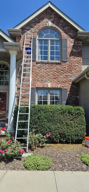 Crew ladder set against a two-story brick home during repair