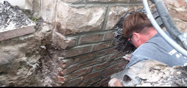 Mason repairing a stone and brick corner on an Omaha home