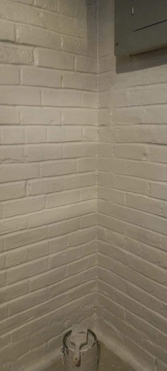 Basement brick wall repointed and sealed with white waterproof coating in Omaha